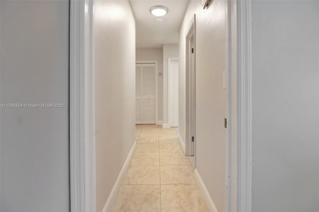 hallway featuring baseboards and light tile patterned floors