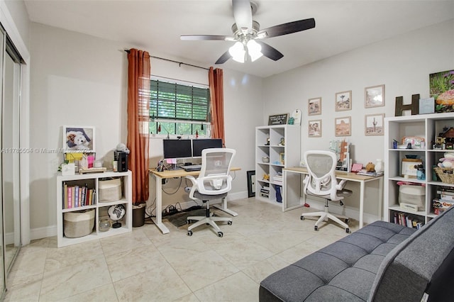 office space with a ceiling fan and baseboards