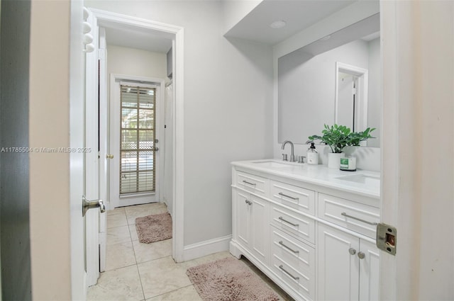 bathroom with baseboards, tile patterned floors, a sink, and double vanity