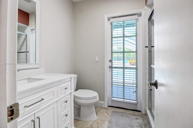 bathroom with a shower stall, toilet, vanity, and baseboards