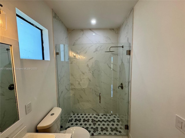 bathroom with toilet, vanity, and a marble finish shower