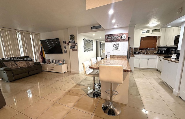 8820 Fontainebleau Blvd Unit 104, Miami, FL 33172 - kitchen with white cabinets, visible vents, a breakfast bar area, and light tile patterned floors