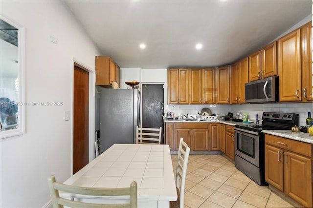 kitchen with stainless steel appliances, a sink, light tile patterned floors, and tasteful backsplash