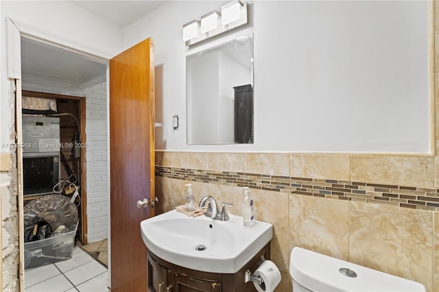 half bath featuring vanity, toilet, tile patterned flooring, and tile walls