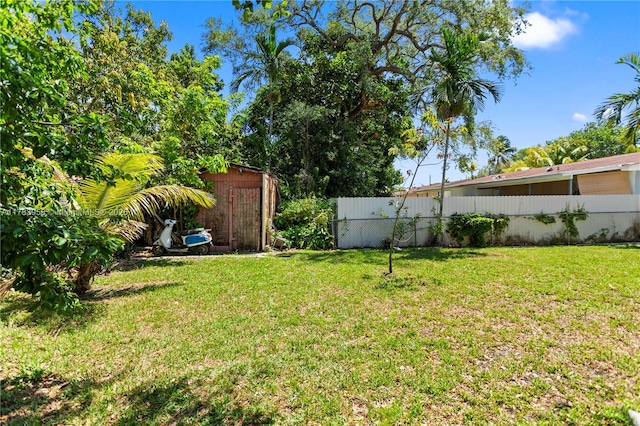 view of yard featuring an outdoor structure, fence, and a shed