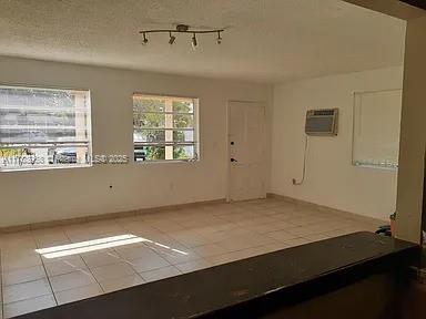 unfurnished room with a wall mounted air conditioner, tile patterned floors, and baseboards