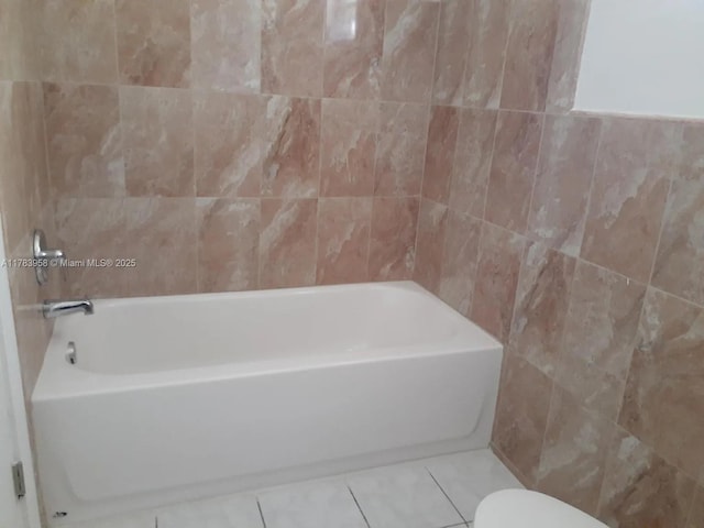 full bath with a tub to relax in, tile walls, and tile patterned floors