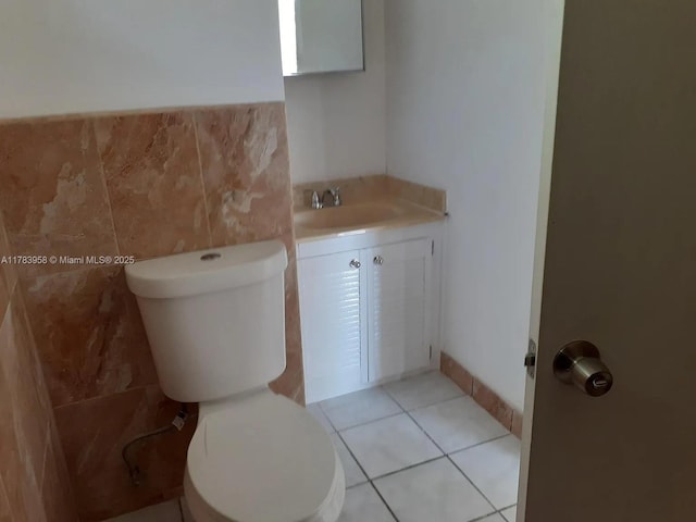 bathroom with tile patterned flooring, toilet, vanity, and tile walls