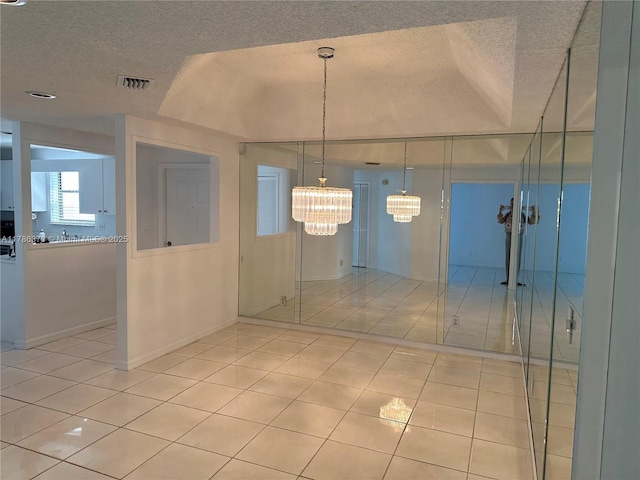 6081 SE Landing Way Unit 8, Stuart, FL 34997 - unfurnished dining area with a textured ceiling, a chandelier, light tile patterned floors, and baseboards