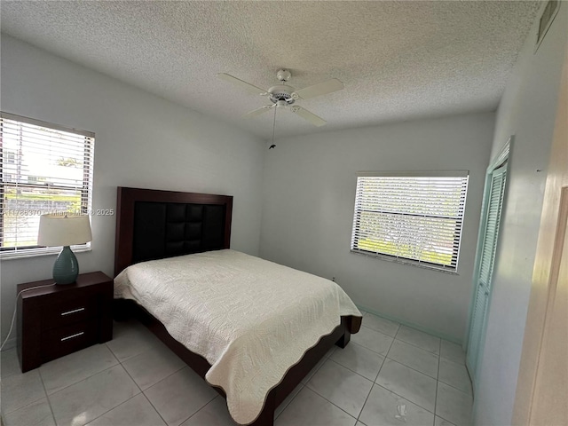 6081 SE Landing Way Unit 8, Stuart, FL 34997 - bedroom featuring multiple windows, light tile patterned flooring, a closet, a ceiling fan, and a textured ceiling