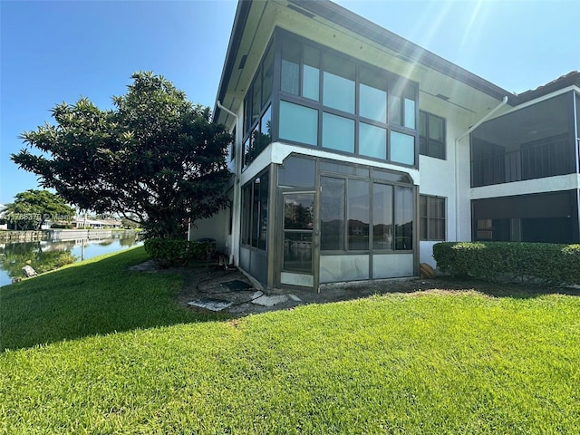 6081 SE Landing Way Unit 8, Stuart, FL 34997 - rear view of house with a water view, a lawn, stucco siding, and a sunroom