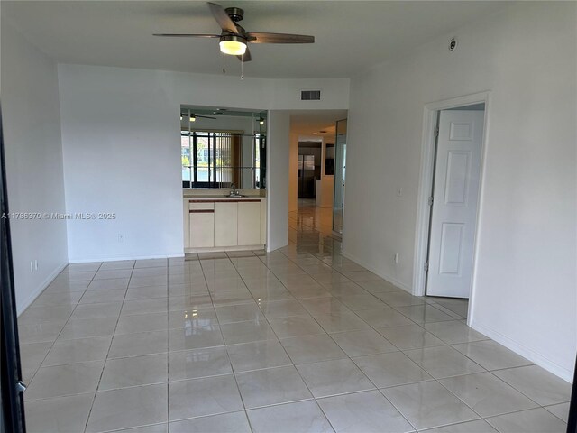 6081 SE Landing Way Unit 8, Stuart, FL 34997 - empty room featuring a ceiling fan, a sink, and light tile patterned floors