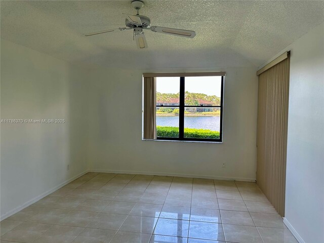 6081 SE Landing Way Unit 8, Stuart, FL 34997 - spare room featuring a ceiling fan, a textured ceiling, light tile patterned floors, baseboards, and a water view