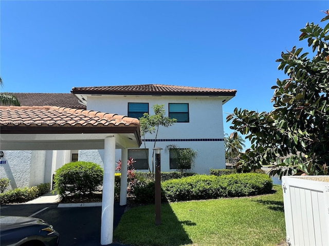 6081 SE Landing Way Unit 8, Stuart, FL 34997 - back of property with stucco siding, a tile roof, a lawn, and covered parking