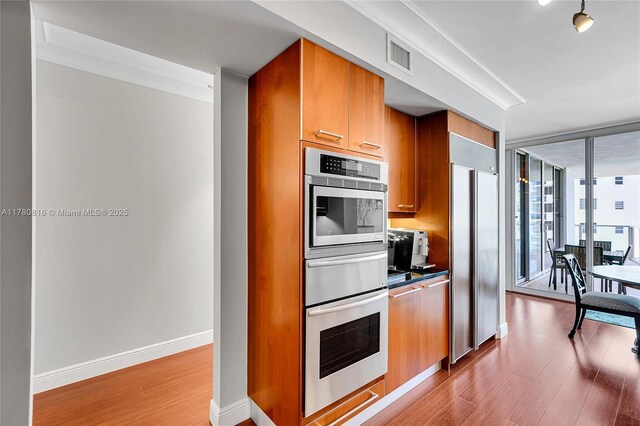 3101 S Ocean Dr Unit 701, Hollywood, FL 33019 - kitchen featuring stainless steel appliances, wood finished floors, expansive windows, baseboards, and brown cabinetry