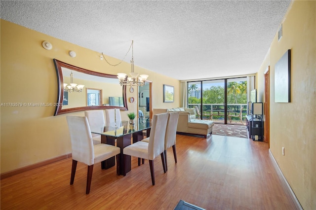 dining room with a chandelier, expansive windows, wood finished floors, and a textured ceiling