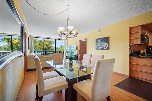 dining space with a textured ceiling, plenty of natural light, visible vents, and an inviting chandelier