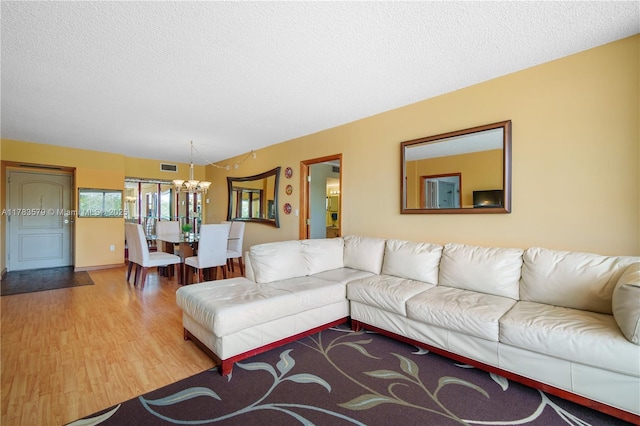 living area featuring visible vents, wood finished floors, a textured ceiling, and an inviting chandelier