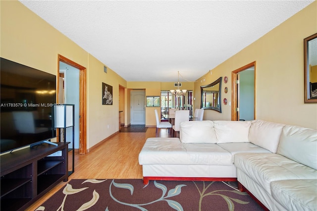 living area with an inviting chandelier, wood finished floors, visible vents, and a textured ceiling