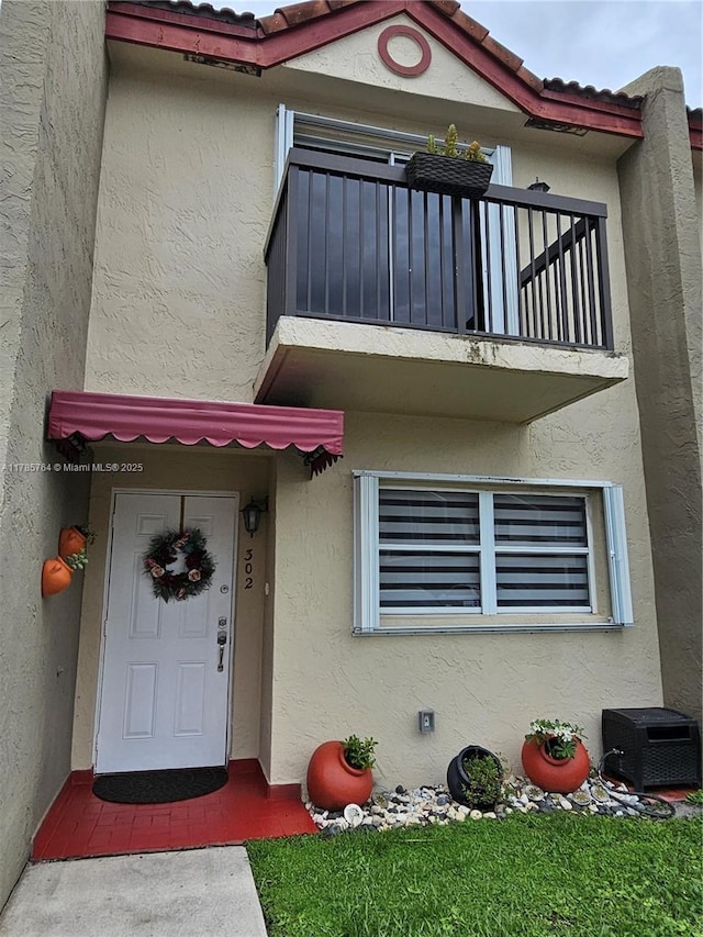doorway to property with stucco siding and a balcony