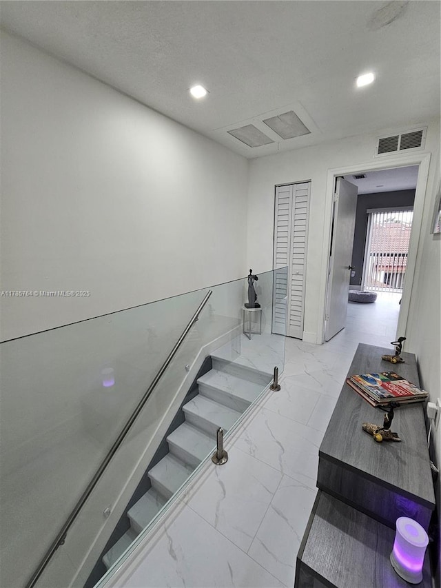 stairway with recessed lighting, visible vents, marble finish floor, and baseboards