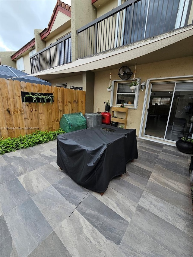 view of patio with fence and a balcony