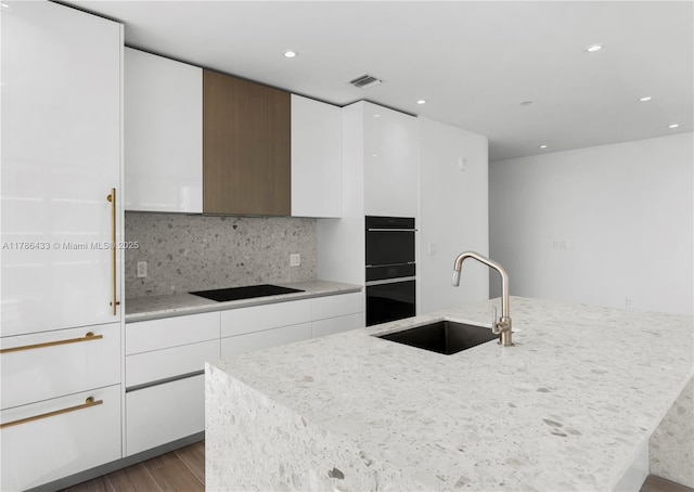 kitchen with a kitchen island with sink, a sink, modern cabinets, wood finished floors, and black appliances