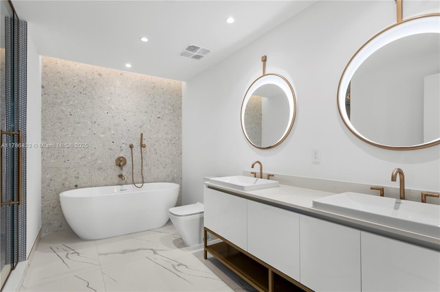 bathroom with a freestanding bath, visible vents, recessed lighting, and a sink