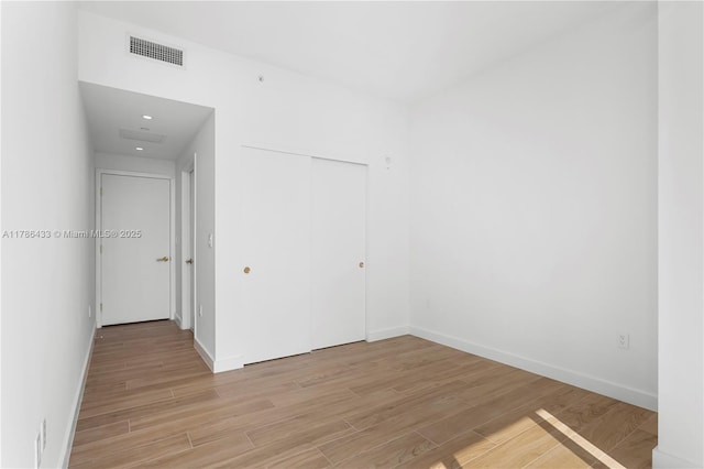 unfurnished room featuring light wood-type flooring, baseboards, and visible vents