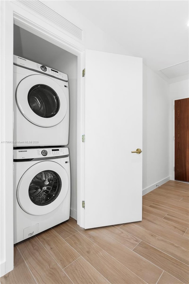 laundry area with light wood-style flooring, stacked washer and clothes dryer, and laundry area