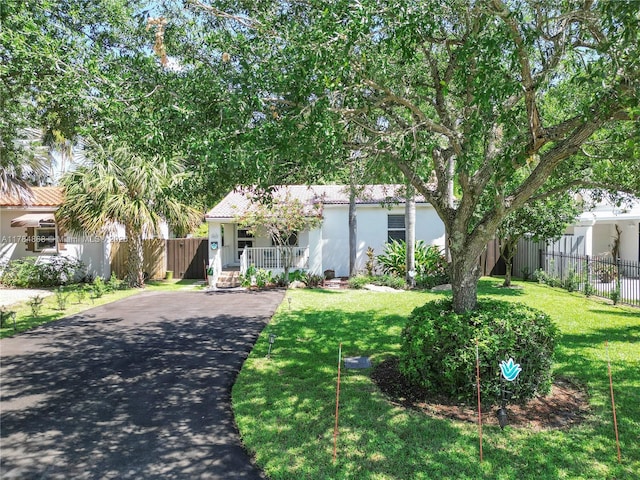 509 SW 13th St, Fort Lauderdale, FL 33315 - view of property hidden behind natural elements with a front lawn, driveway, fence, a porch, and stucco siding