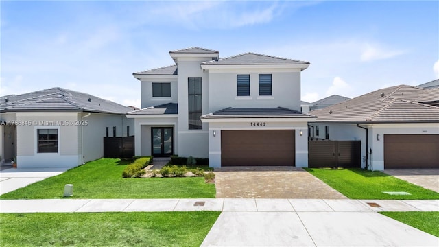 view of front of property featuring a tile roof, a front lawn, driveway, stucco siding, and french doors