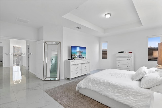 bedroom with marble finish floor, visible vents, and a tray ceiling