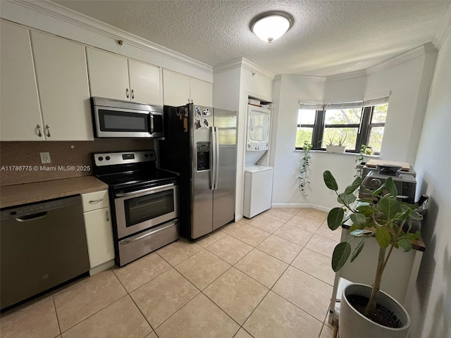 22701 SW 88th Pl Unit 203-9, Cutler Bay, FL 33190 - kitchen featuring appliances with stainless steel finishes, stacked washing machine and dryer, ornamental molding, a textured ceiling, and light tile patterned floors