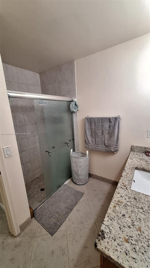 full bath featuring baseboards, vanity, tile patterned flooring, and a stall shower