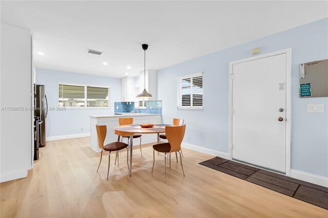 632 Hummingbird Ln, Delray Beach, FL 33445 - kitchen featuring light wood-style floors, white cabinets, decorative backsplash, baseboards, and healthy amount of natural light