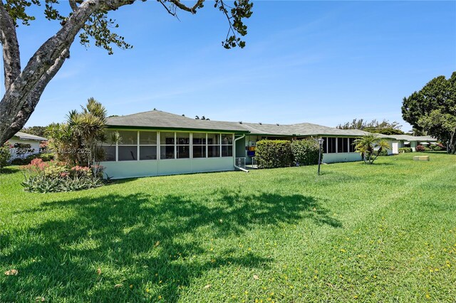 632 Hummingbird Ln, Delray Beach, FL 33445 - rear view of house with a sunroom and a lawn