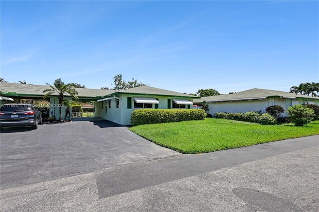 632 Hummingbird Ln, Delray Beach, FL 33445 - ranch-style house with a front yard, asphalt driveway, a carport, and stucco siding