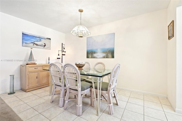 dining area featuring an inviting chandelier, light tile patterned floors, and baseboards