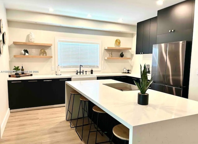 2360 SW 12th St, Miami, FL 33135 - kitchen with freestanding refrigerator, open shelves, light wood-style floors, dark cabinetry, and a sink