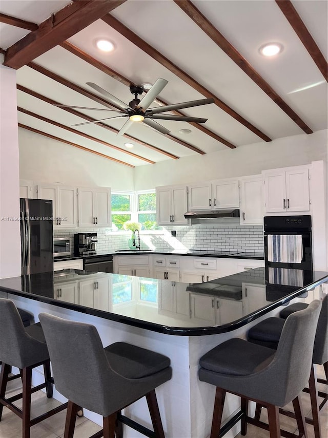 kitchen featuring black appliances, dark countertops, and a sink