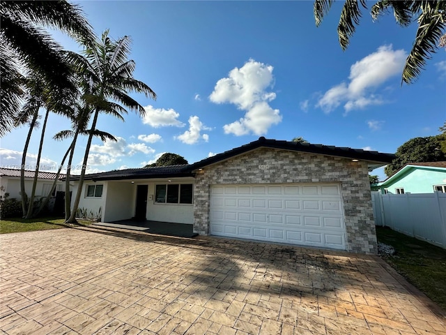 5424 Garfield St, Hollywood, FL 33021 - ranch-style house featuring stone siding, stucco siding, decorative driveway, fence, and a garage