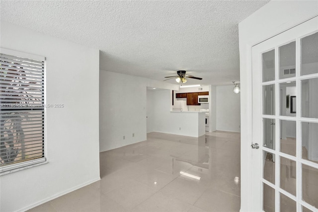 unfurnished room featuring a ceiling fan, visible vents, a textured ceiling, and light tile patterned floors
