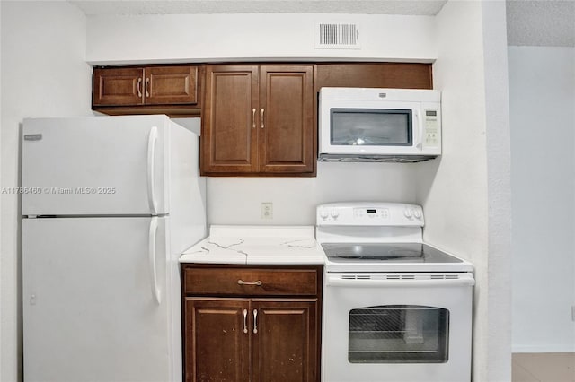 kitchen featuring visible vents, light countertops, white appliances, and a textured ceiling