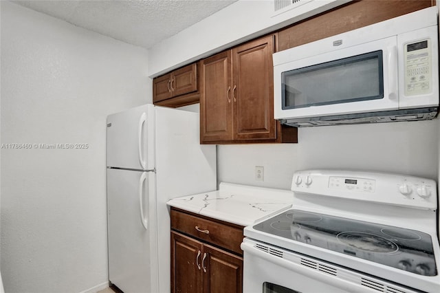 kitchen with light countertops, white appliances, and a textured ceiling