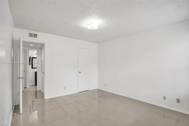 unfurnished bedroom featuring a textured ceiling, visible vents, and baseboards