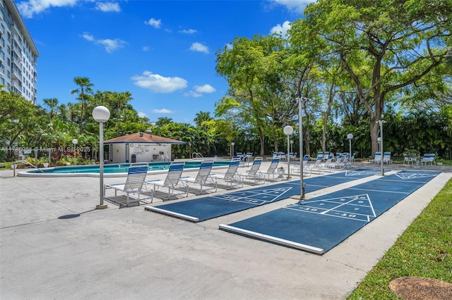 3800 Hillcrest Dr Unit 210, Hollywood, FL 33021 - view of property's community featuring a pool, shuffleboard, fence, view of wooded area, and a patio area