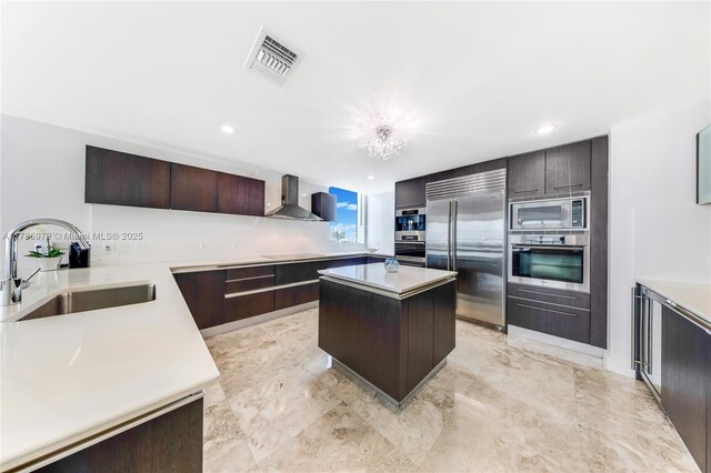 17001 Collins Ave Unit 2401, Sunny Isles Beach, FL 33160 - kitchen featuring visible vents, a sink, light countertops, built in appliances, and wall chimney exhaust hood