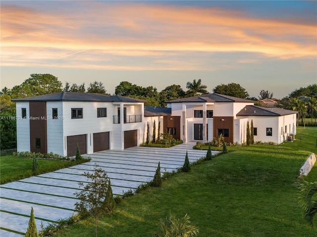 modern home featuring a lawn, decorative driveway, a balcony, and a garage