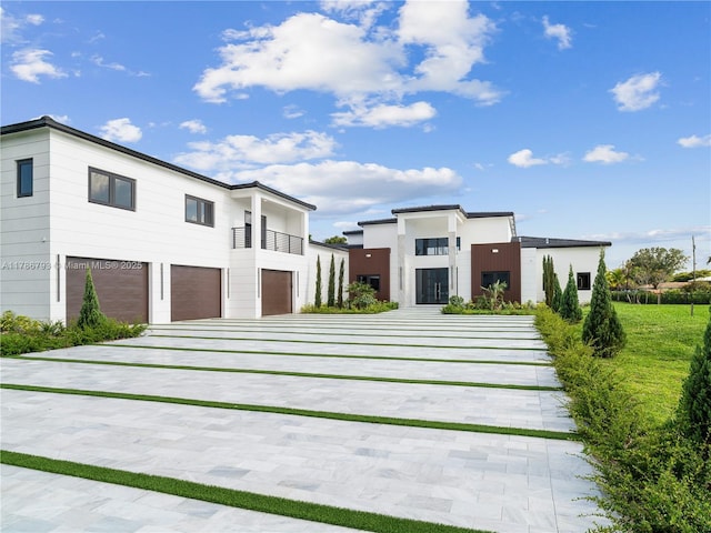 contemporary home with an attached garage, a balcony, and concrete driveway
